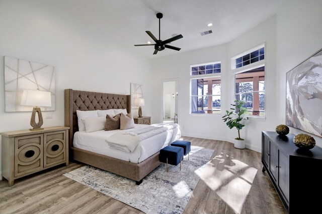bedroom with light wood finished floors, visible vents, connected bathroom, baseboards, and ceiling fan