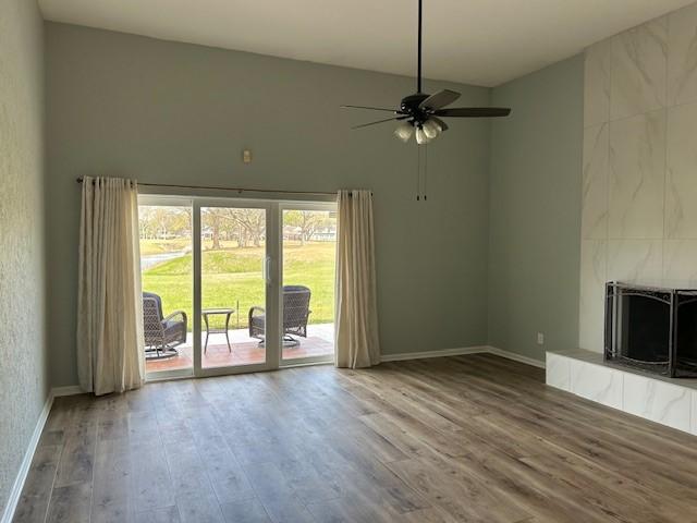 unfurnished living room featuring baseboards, wood finished floors, and a ceiling fan