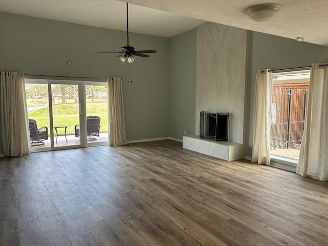 unfurnished living room featuring a fireplace, baseboards, ceiling fan, and wood finished floors