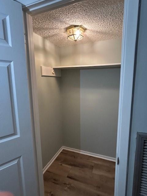 interior space featuring baseboards, a textured ceiling, and wood finished floors