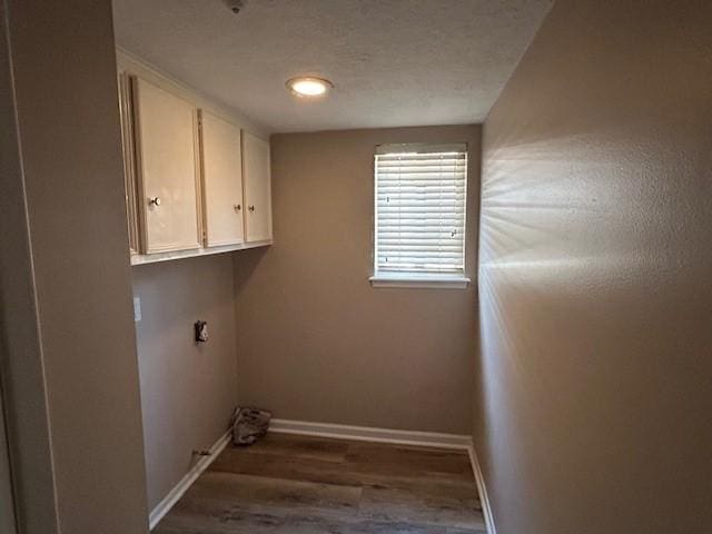 washroom featuring cabinet space, wood finished floors, baseboards, and a textured ceiling