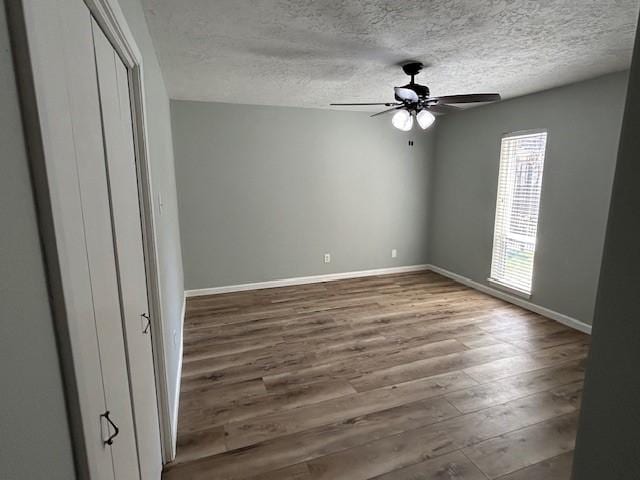 unfurnished bedroom with wood finished floors, baseboards, a closet, and a textured ceiling