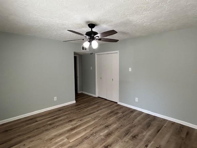 unfurnished bedroom with visible vents, a textured ceiling, baseboards, and wood finished floors