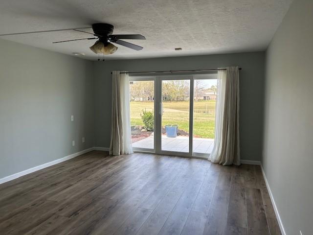 empty room with dark wood-style floors, a textured ceiling, baseboards, and a ceiling fan