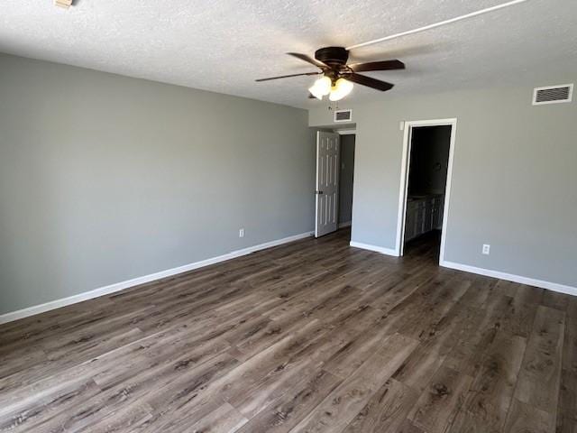 interior space featuring baseboards, visible vents, dark wood-style flooring, and a textured ceiling