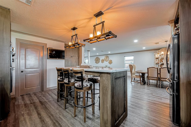 kitchen featuring dark wood-type flooring, a chandelier, light countertops, ornamental molding, and a textured ceiling