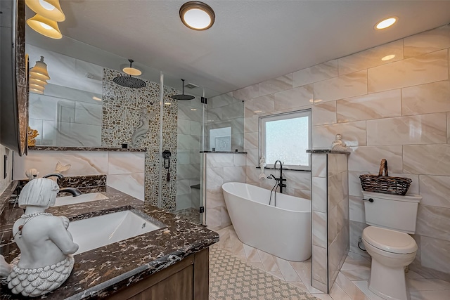 full bathroom featuring vanity, tile walls, a shower stall, and a freestanding bath