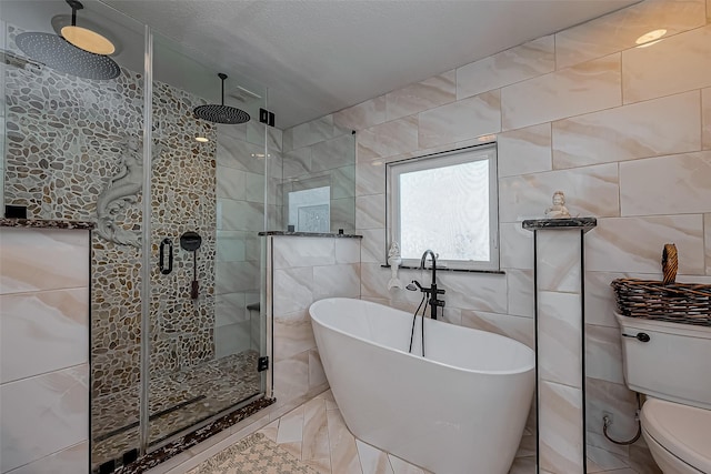 bathroom featuring toilet, a stall shower, a soaking tub, marble finish floor, and tile walls