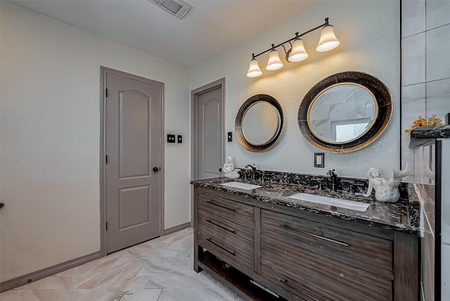 full bath featuring a sink, visible vents, baseboards, and double vanity