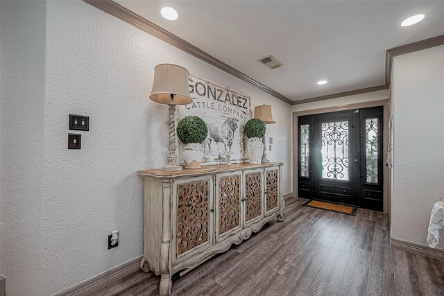 entrance foyer featuring wood finished floors, visible vents, a textured wall, and ornamental molding