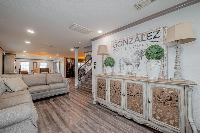 living room with wood finished floors, visible vents, decorative columns, stairs, and a chandelier