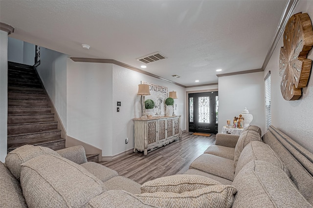 living area featuring wood finished floors, visible vents, ornamental molding, stairs, and a textured ceiling