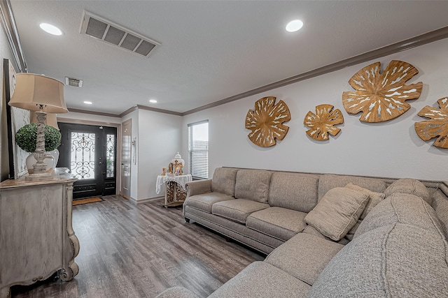 living area featuring visible vents, ornamental molding, baseboards, and wood finished floors