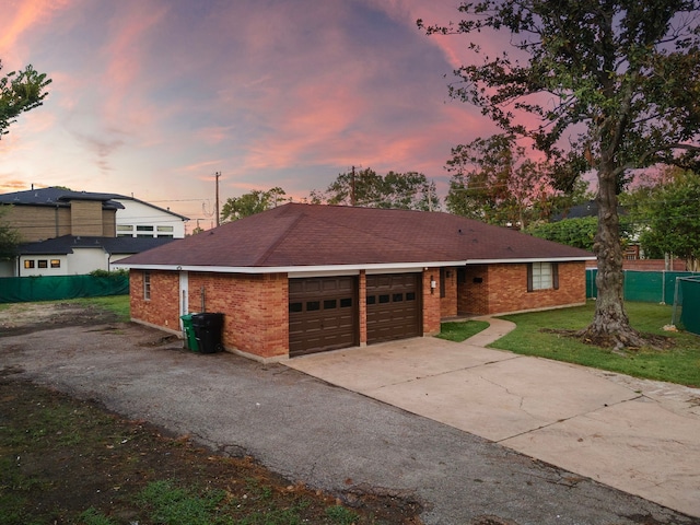 ranch-style house featuring brick siding, an attached garage, fence, a front yard, and driveway