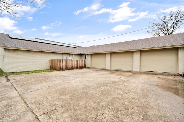 garage featuring roof mounted solar panels and fence