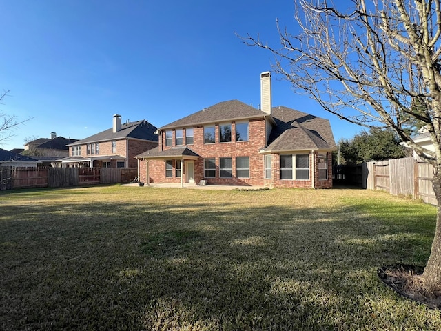 rear view of property with a lawn, brick siding, and a fenced backyard