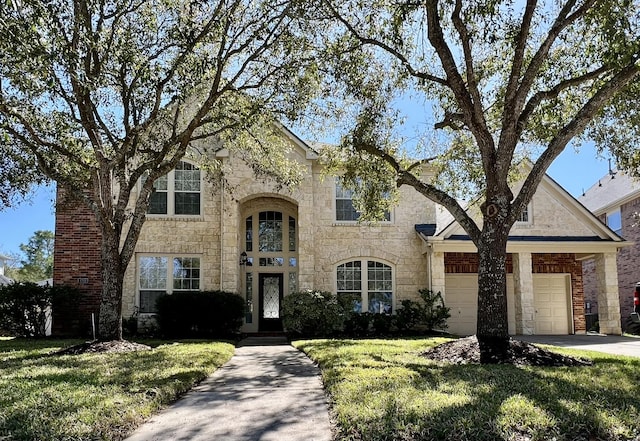 traditional-style house with stone siding, an attached garage, concrete driveway, and a front lawn