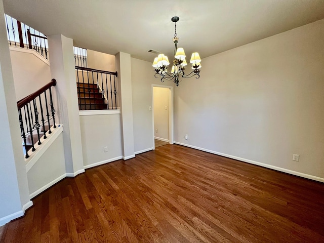 spare room featuring stairs, wood finished floors, baseboards, and a chandelier