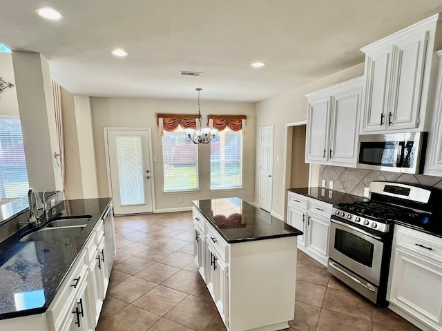 kitchen with visible vents, a sink, a kitchen island, appliances with stainless steel finishes, and a chandelier