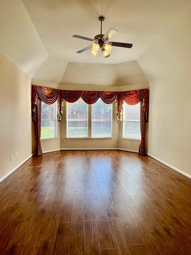 empty room featuring a wealth of natural light, wood finished floors, vaulted ceiling, and ceiling fan