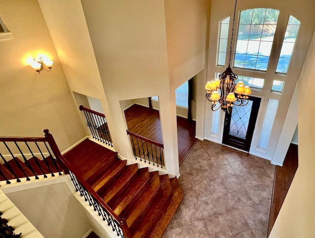 entryway with stairway, a high ceiling, baseboards, and a chandelier