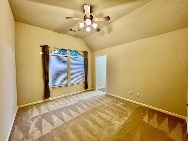 carpeted empty room with lofted ceiling, baseboards, visible vents, and ceiling fan