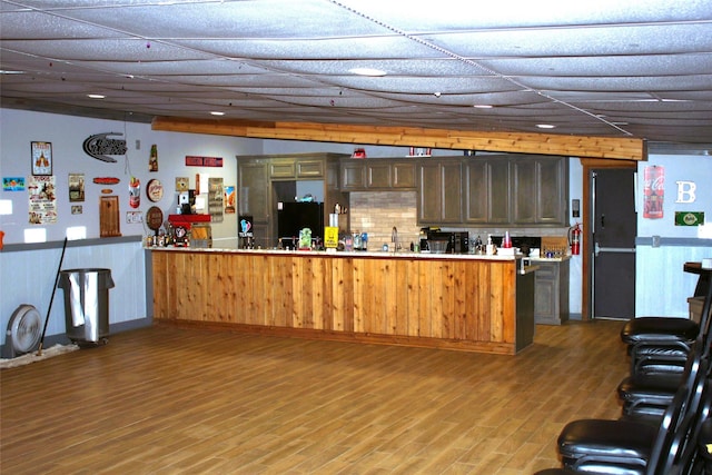 kitchen featuring a peninsula, wood finished floors, freestanding refrigerator, and light countertops