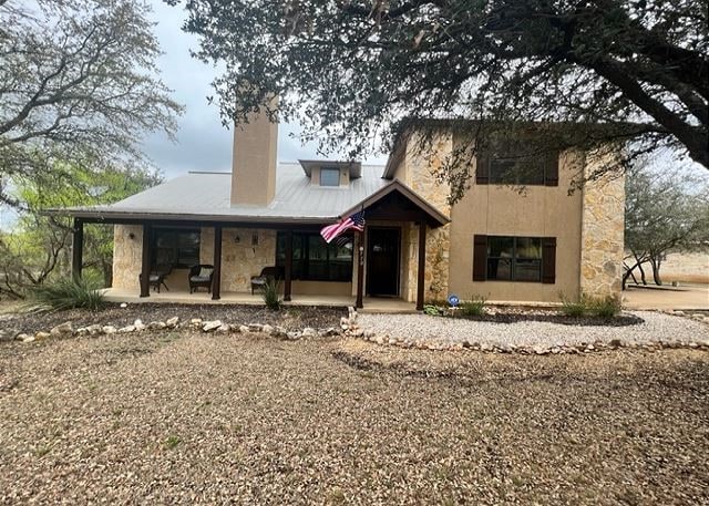 view of front of home with stone siding and a chimney