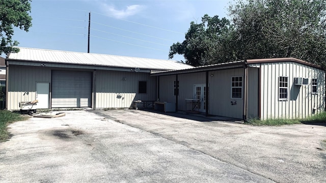 exterior space featuring aphalt driveway, a garage, and metal roof