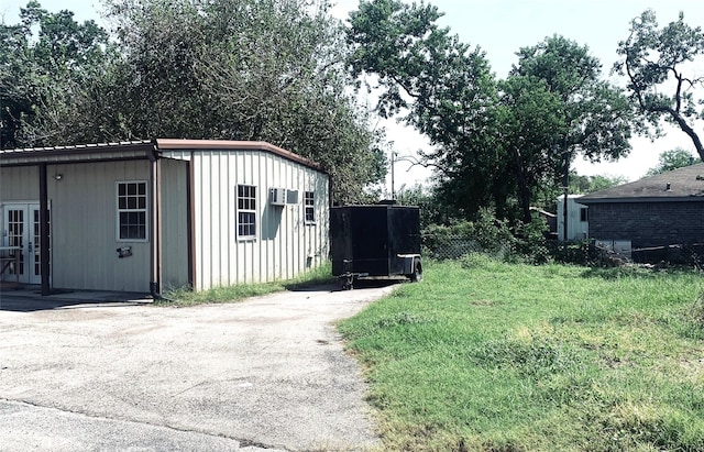 view of outdoor structure featuring french doors, a wall mounted AC, and driveway