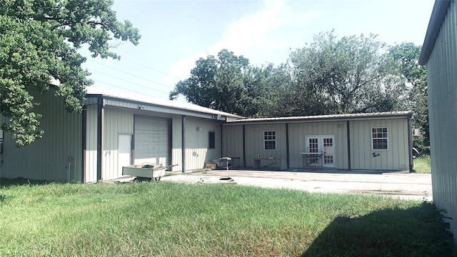 rear view of property with an outbuilding, a garage, a lawn, and board and batten siding