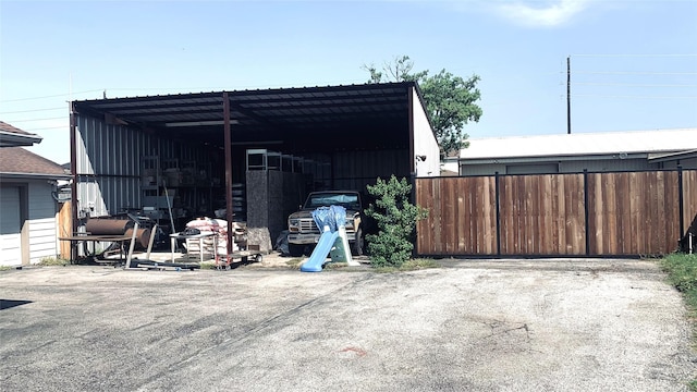 view of parking with an outbuilding and fence