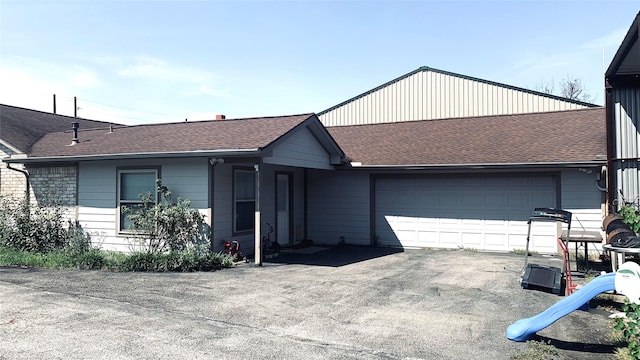 view of front of home featuring an attached garage, driveway, and roof with shingles