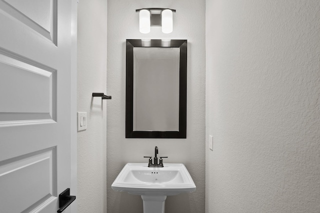 bathroom with a textured wall and a sink