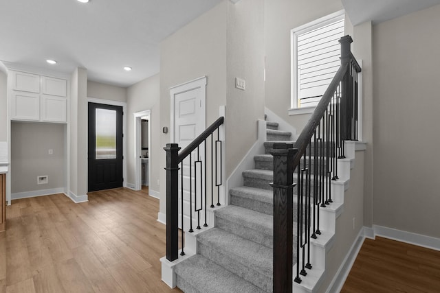 foyer entrance featuring stairway, baseboards, and light wood-type flooring