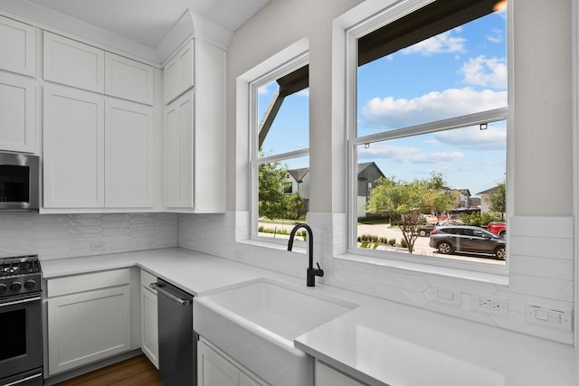 kitchen featuring black range with gas cooktop, stainless steel microwave, light countertops, and a sink