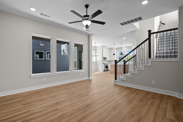 interior space featuring visible vents, light wood finished floors, ceiling fan, and stairway