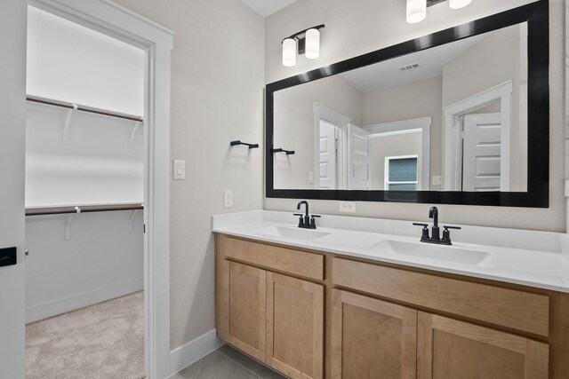 bathroom with double vanity, visible vents, baseboards, and a sink