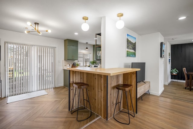 kitchen featuring a breakfast bar, a wealth of natural light, wooden counters, and green cabinetry