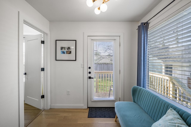 doorway to outside with a chandelier, baseboards, and wood finished floors