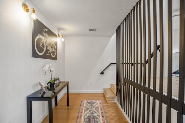 corridor with visible vents, baseboards, and wood finished floors