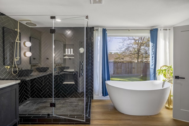 bathroom with a stall shower, a freestanding bath, vanity, and wood finish floors