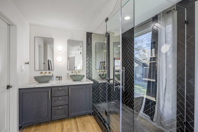 full bath featuring double vanity, wood finished floors, a stall shower, and a sink