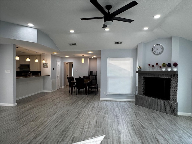 unfurnished living room with vaulted ceiling, visible vents, and a tile fireplace