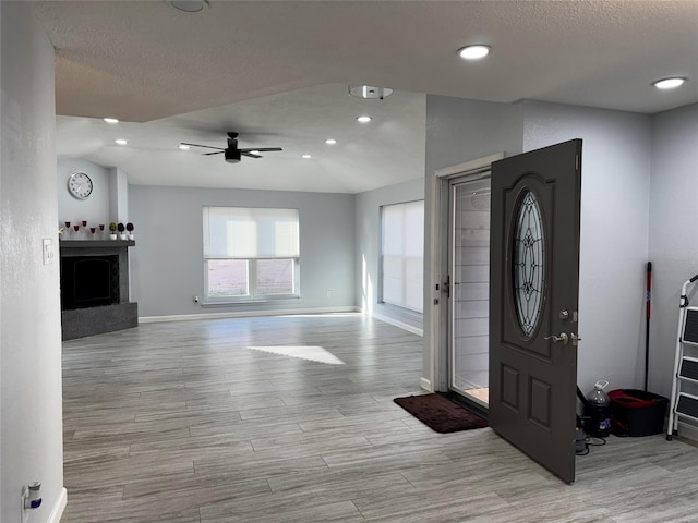 entrance foyer featuring a textured ceiling, wood finished floors, baseboards, and ceiling fan