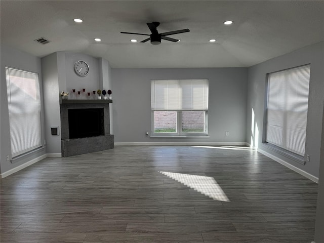 unfurnished living room featuring dark wood-style floors, a fireplace with raised hearth, a ceiling fan, and lofted ceiling