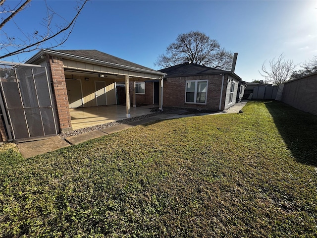 back of house featuring a yard, brick siding, a fenced backyard, and a patio area