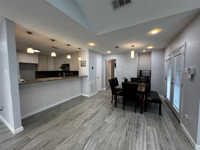 dining room with baseboards, wood finished floors, visible vents, and a textured ceiling