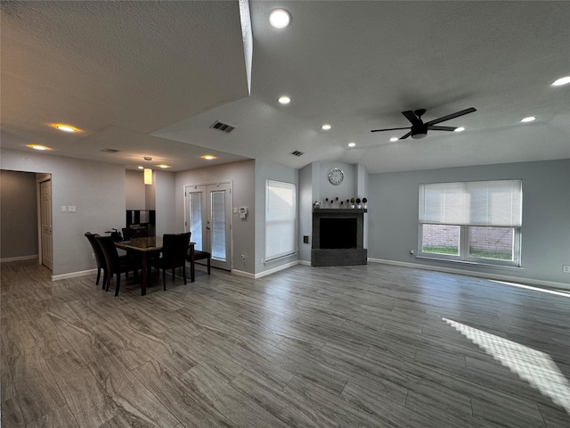 living room featuring ceiling fan, visible vents, wood finished floors, and vaulted ceiling