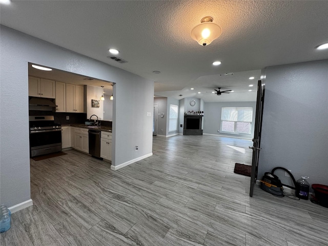 kitchen with visible vents, open floor plan, dishwashing machine, stainless steel stove, and a sink